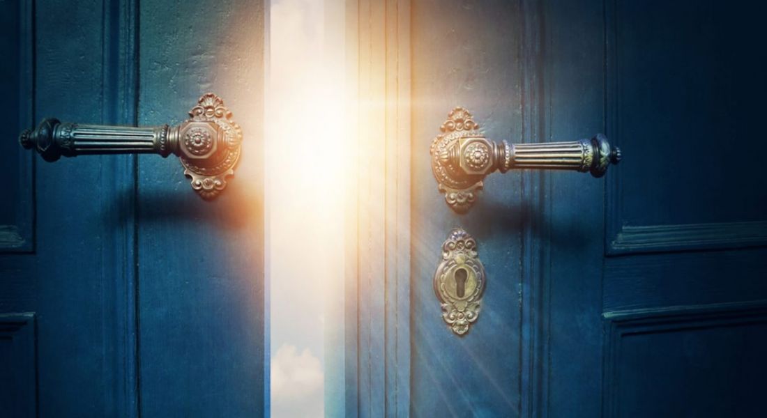 Two vintage navy blue doors with gold handles opening to reveal sunshine, depicting breaking into cybersecurity.
