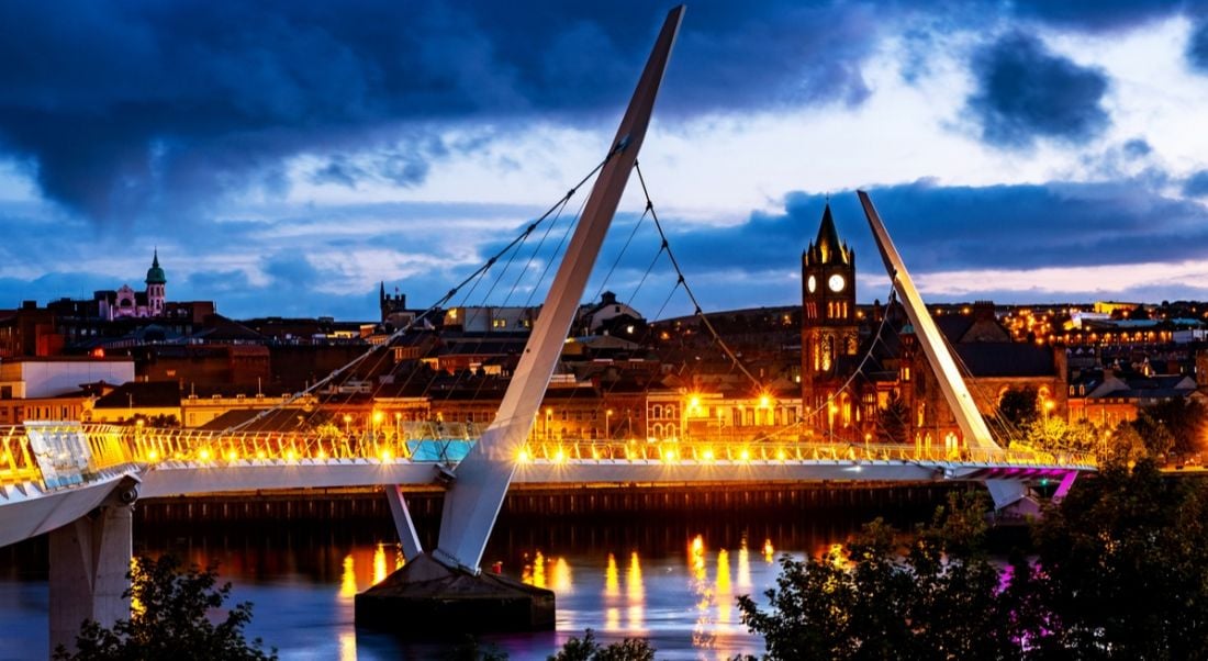 View of a white modern architecture bridge in Derry illuminated at twilight. Alchemy Technology Services will be based here.