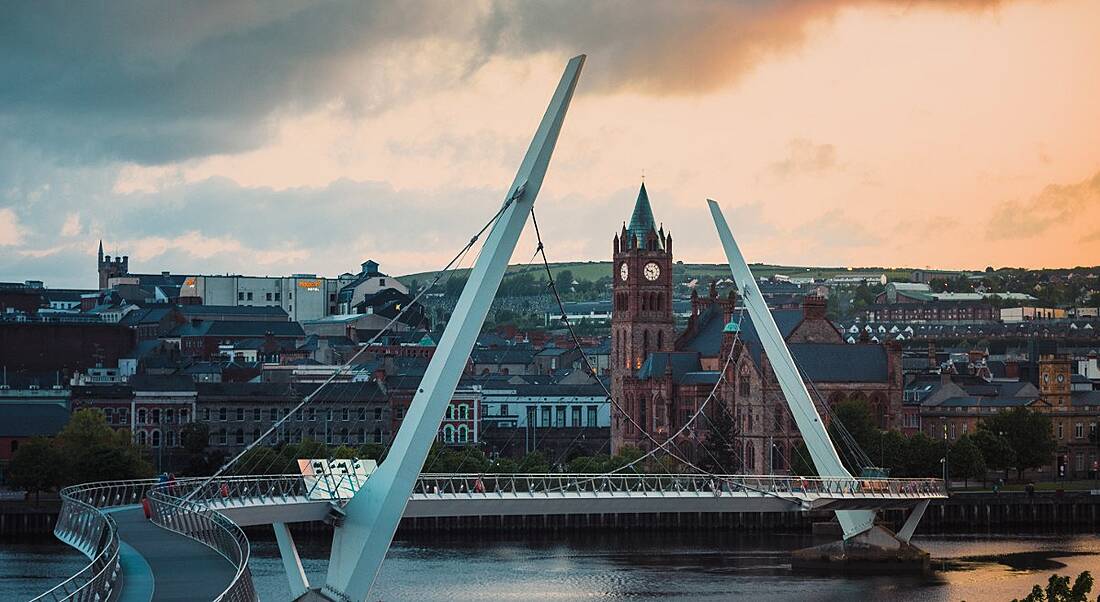 A view of Derry city from the Peace Bridge under a cloudy sky.