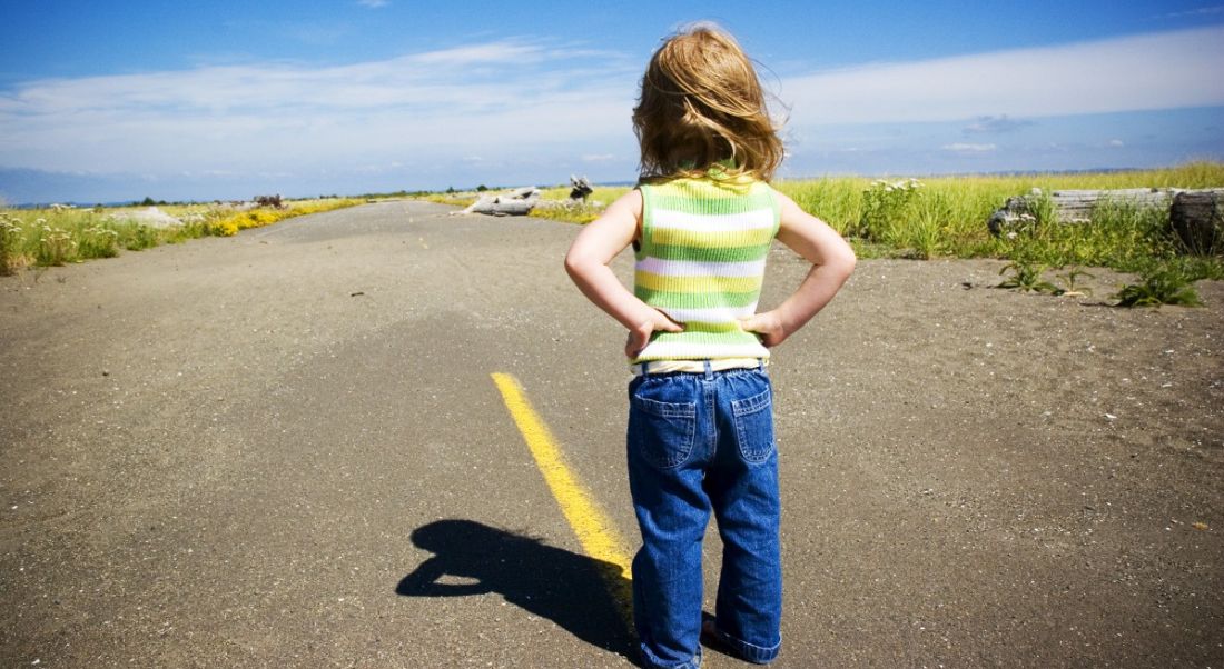 A little girl facing a long road with her hands on her hips. She means business when it comes to the future of work.