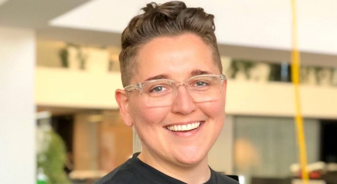A headshot of a smiling young woman with short hair and glasses. She works at Spotify.