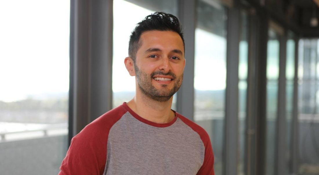 Headshot of smiling young man with dark hair in a casual long-sleeved top in the Oath office in Dublin.