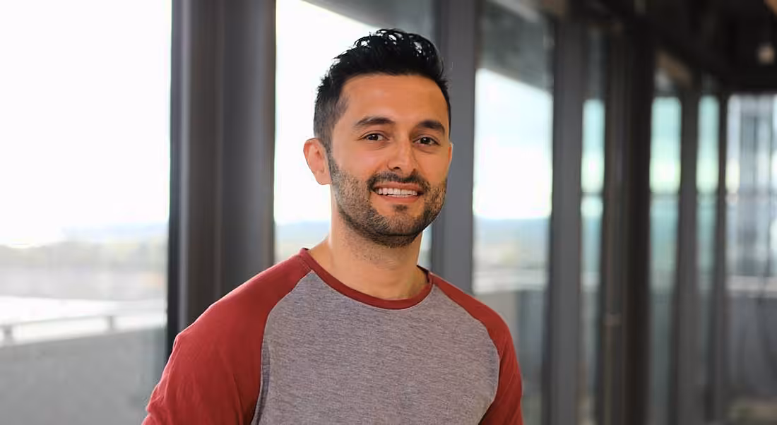 Headshot of smiling young man with dark hair in a casual long-sleeved top in the Oath office in Dublin.