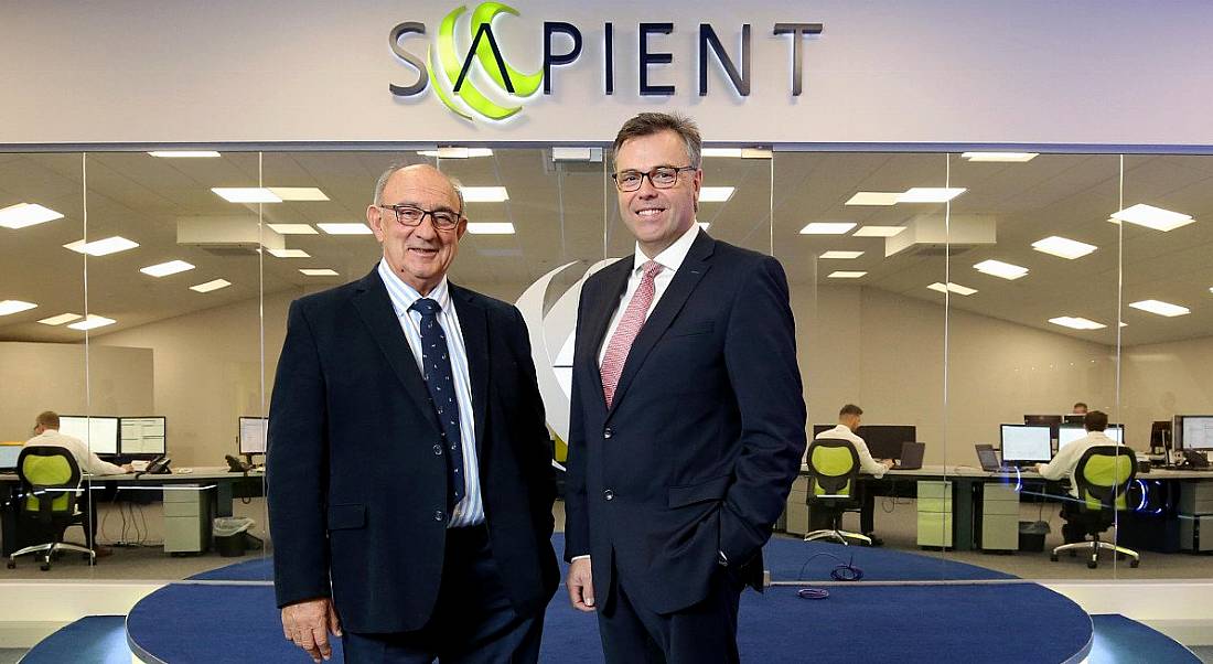 Two men in suits, the CEOs of Camlin and Invest NI respectively, smiling under a green sign that says ‘Sapient’.