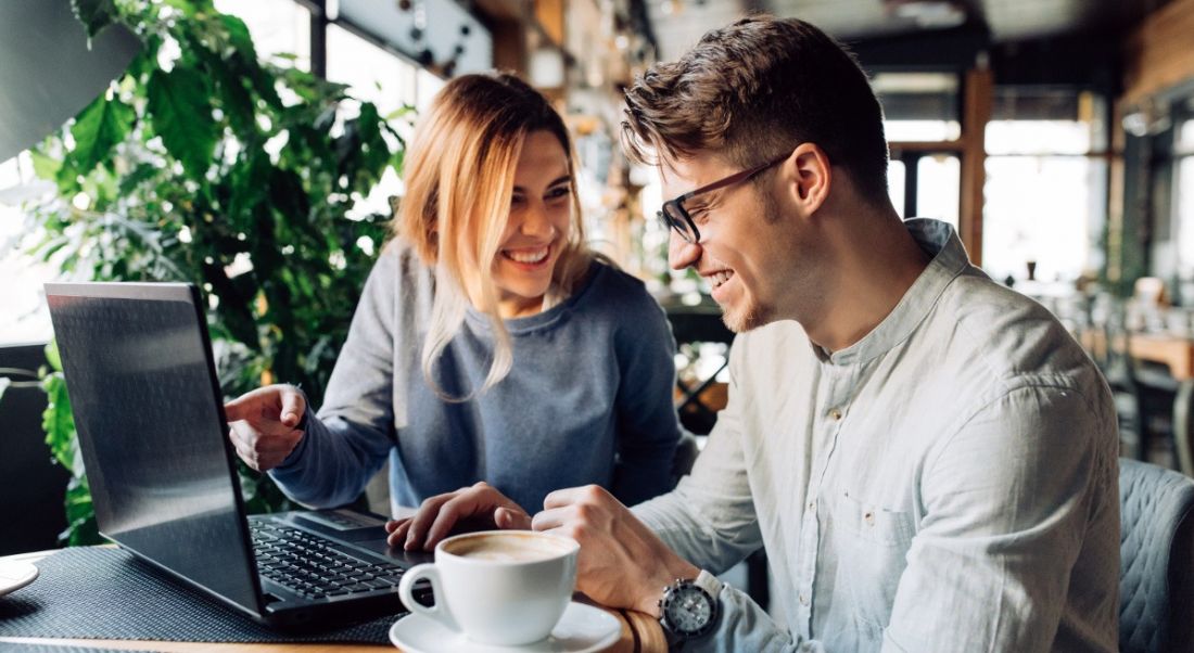 A young man and a woman smiling with glee while looking at jobs announcements made during October.