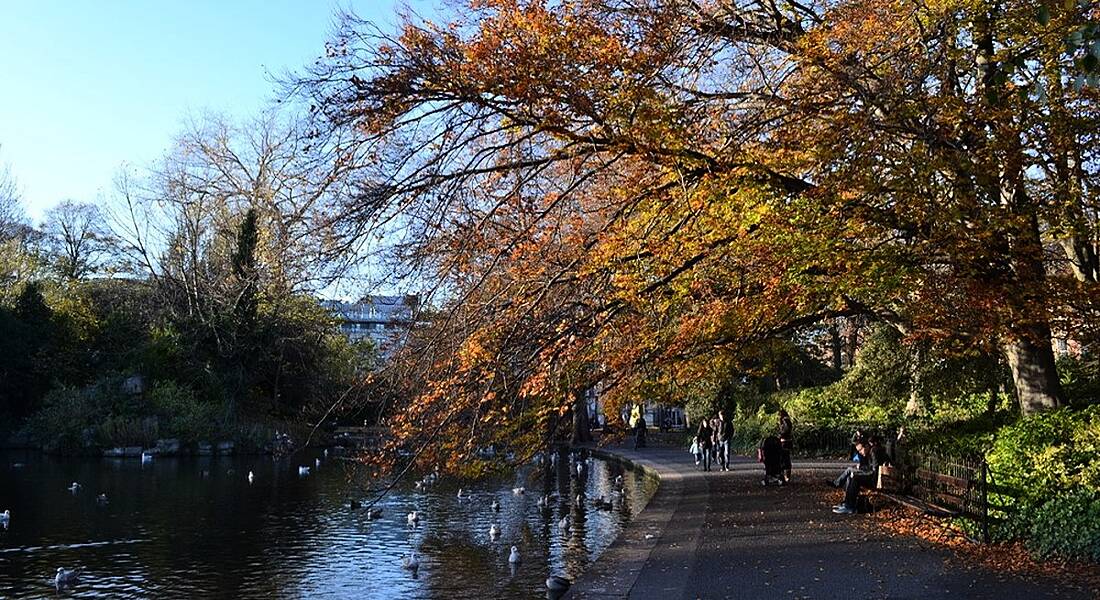 People walking alongside lake in St Stephen's Green Dublin on an autumn afternoon.