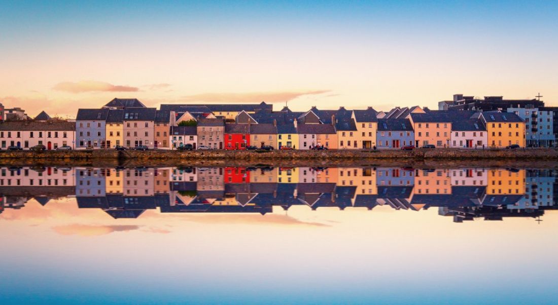 Beautiful view of Galway city from the water with city reflecting on shore.