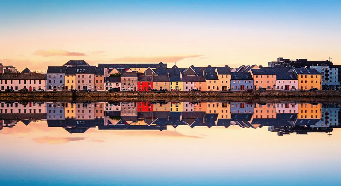 Beautiful view of Galway city from the water with city reflecting on shore.