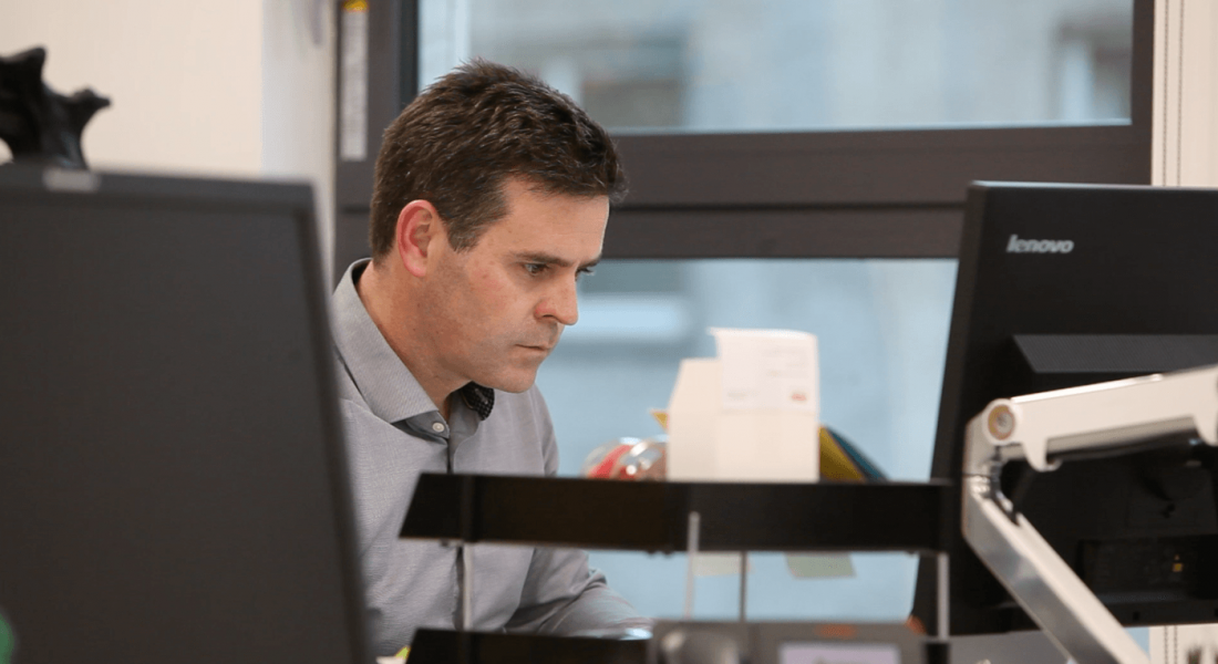 A man with dark hair working at a computer in the Aon office in Dublin.