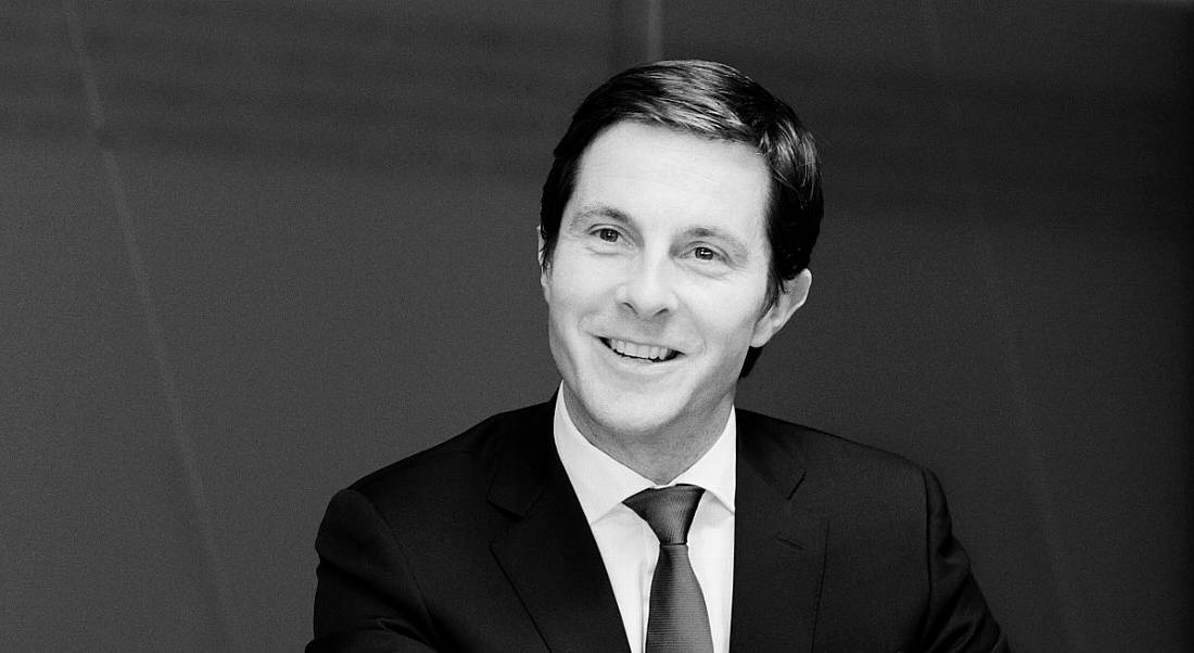 A black and white photo of a smiling man in a formal suit. He is the financial services advisory lead in EY.