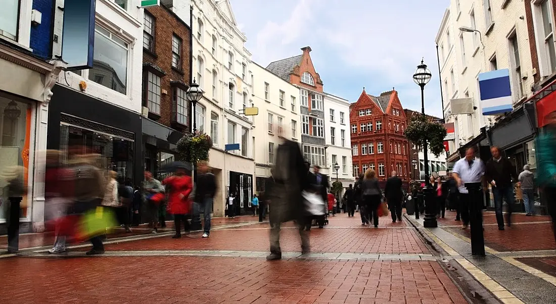 people quickly walking on small, narrow street in cloudy weather.