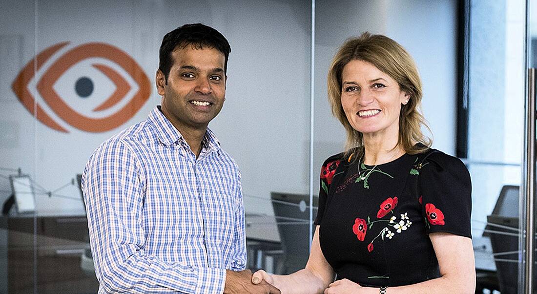 A man and a woman shaking hands while looking at the camera, celebrating the announcement by ThousandEyes.