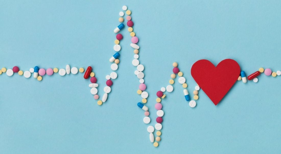 Cardiogram made of colourful pills and a red paper heart, depicting a life sciences and pharma concept.