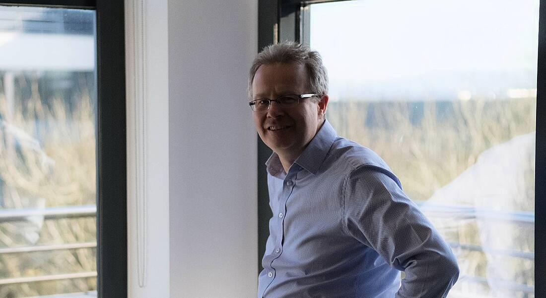 A man with grey hair and glasses in a light blue shirt in an office in Fidelity Investments.