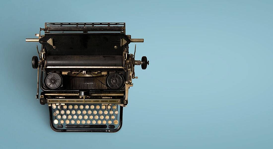 Vintage black typewriter against blue background.