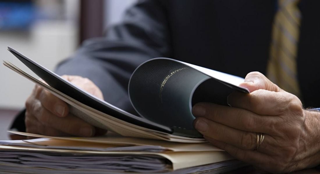 View of hands of a business man reading a reference amid a pile of job application paperwork.