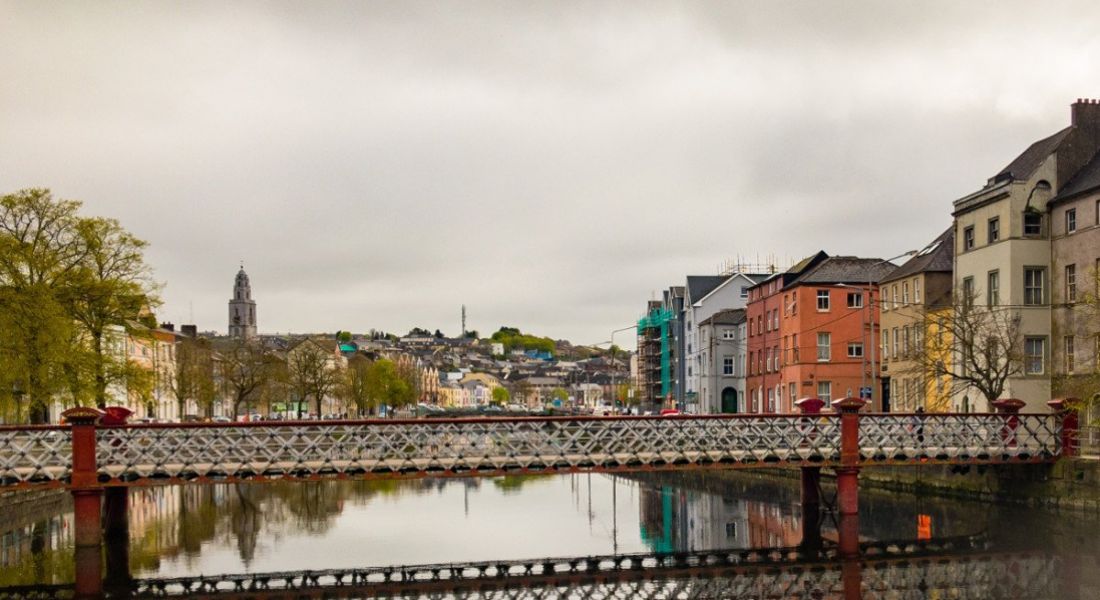 A bridge over the River Lee in Cork, surrounded by greenery and colourful apartment blocks.