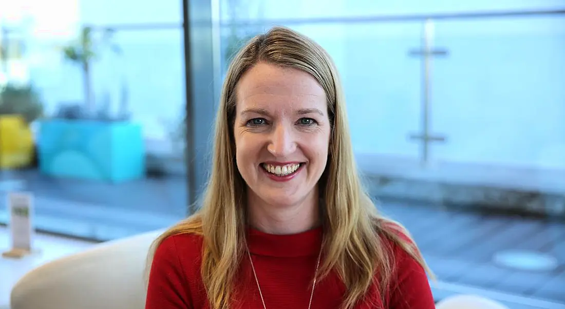 A close-up of a smiling blonde woman in an office. She is Sinead Smith and she’s talking about the lives of working parents.