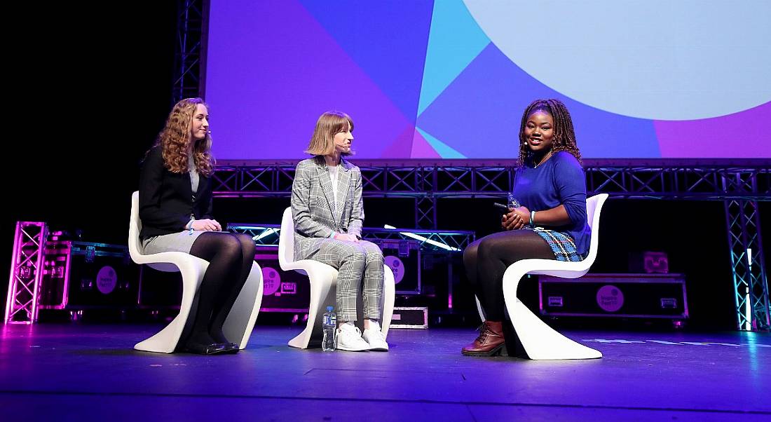 Three young women sitting in chairs on a stage at Inspirefest. They are discussing life for women in STEM.