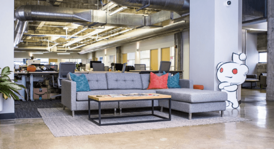 Reddit's San Francisco office with little alien mascot standing beside a large sofa.