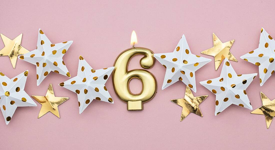 A gold number six candle on a pink background surrounded by decorative stars. It represents six fintech myths.