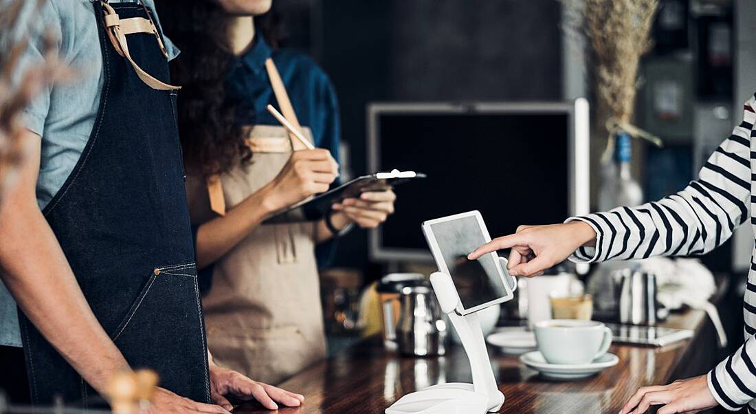 People using restaurant technology in a bustling cafe setting.