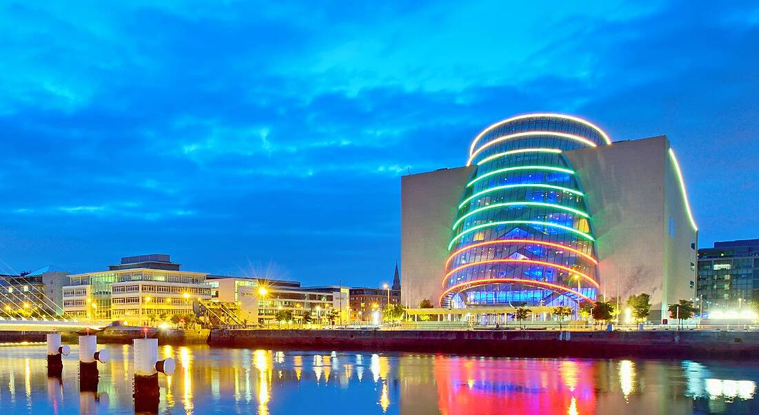 View of Dublin city convention centre and financial district illuminated at night.