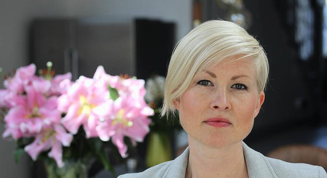 View of young woman with icy platinum pixie cut hair and blue eyes looking determined facing the camera. Works at New Relic.