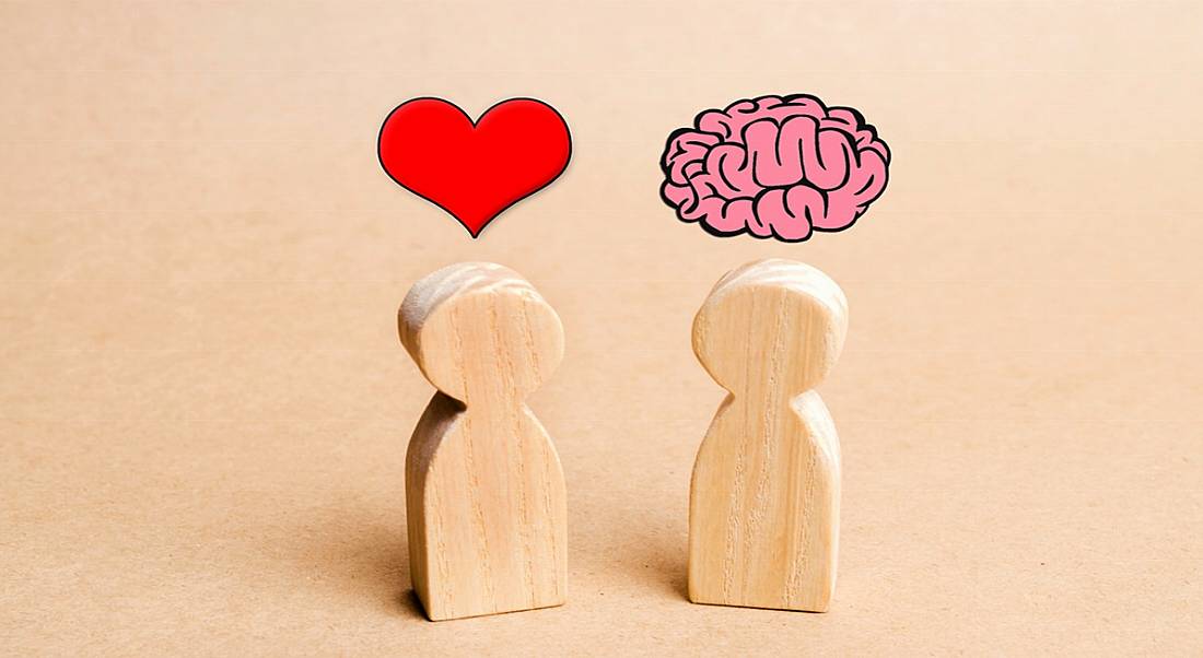 Wooden figures on a table, one has a cartoon heart above its head and the other has a cartoon brain above its head.