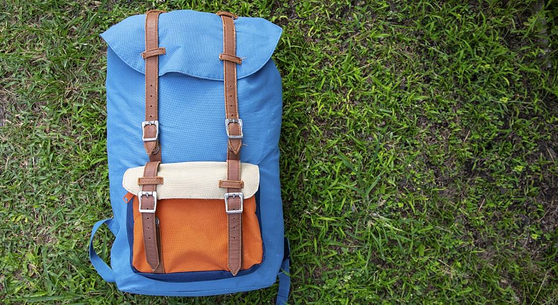 A blue and orange rucksack laid down on grass.