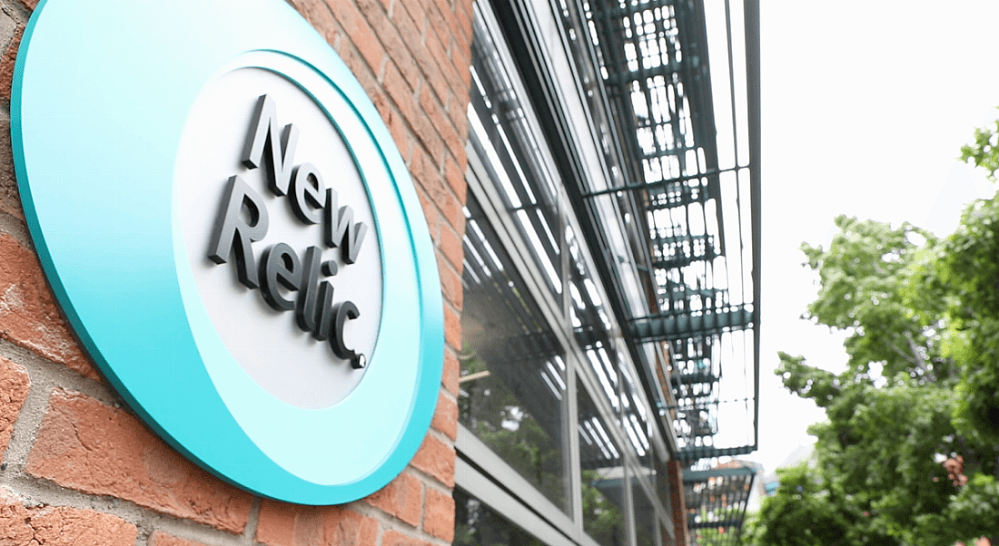 Outside photo of New Relic office building, with blue and white sign reading 'New Relic' against a red brick building wall.