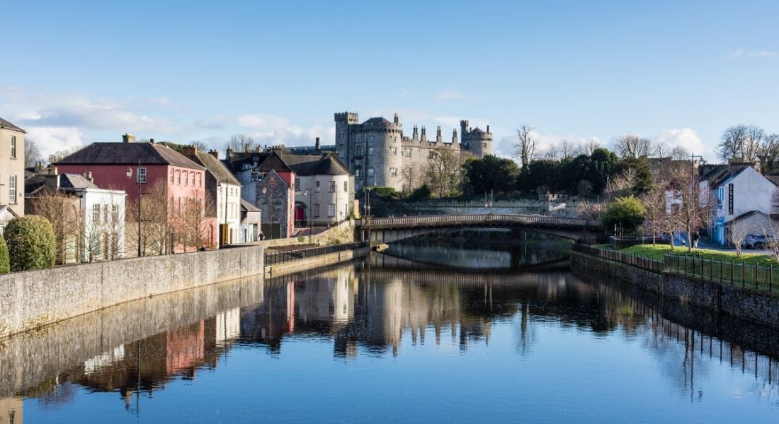 View of old historic town skyline being reflected on the water of a river running through the town.