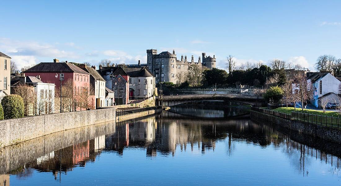 View of old historic town skyline being reflected on the water of a river running through the town.