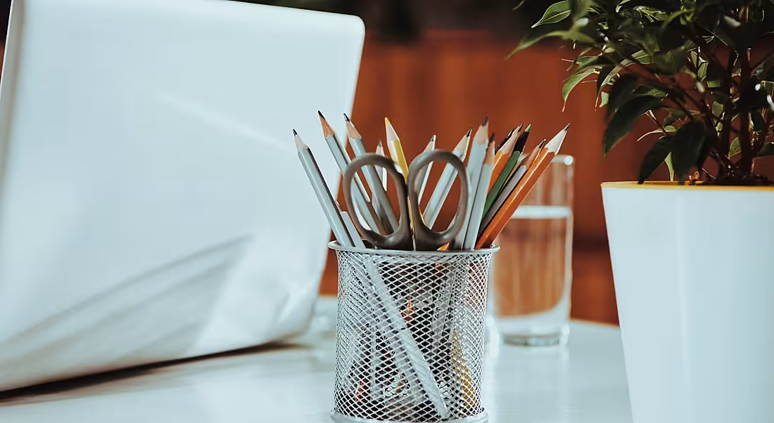 View of pencils on a desk next to a laptop in a modern office.