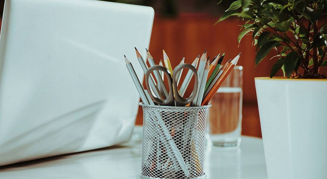 View of pencils on a desk next to a laptop in a modern office.