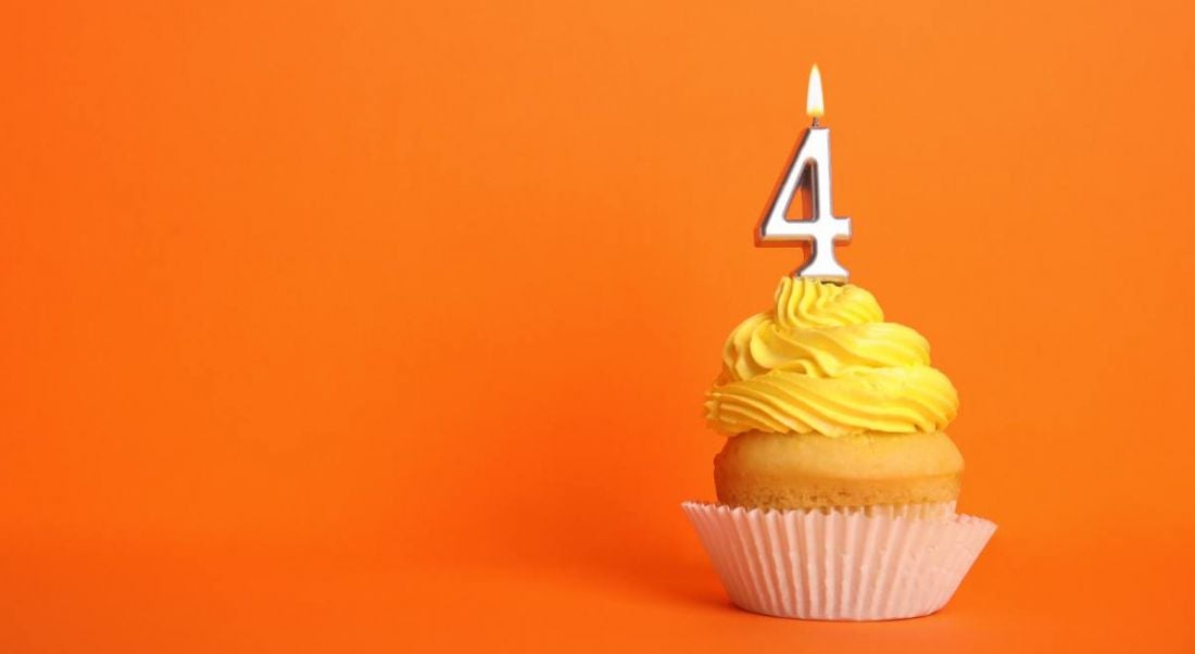 Birthday cupcake with number four candle on orange background.