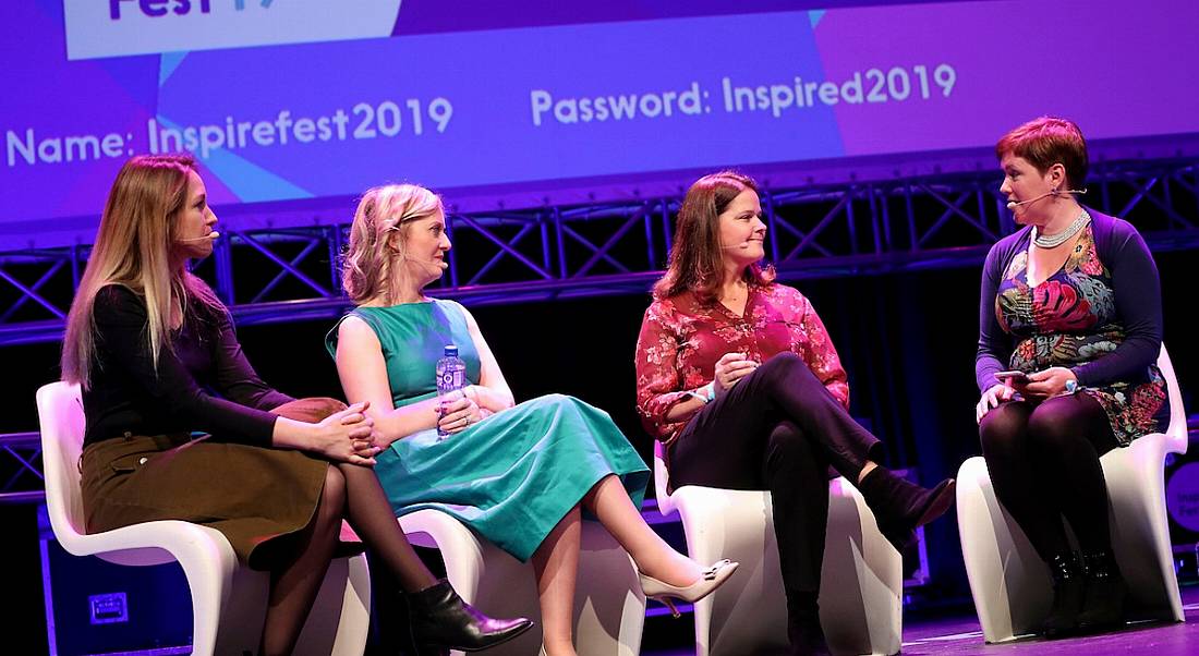 Four women are sitting on a stage and talking to each other.