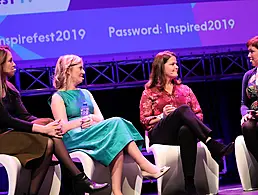 A man in a slate grey suit grinning widely at a crowd at the Inspirefest 2019 conference.