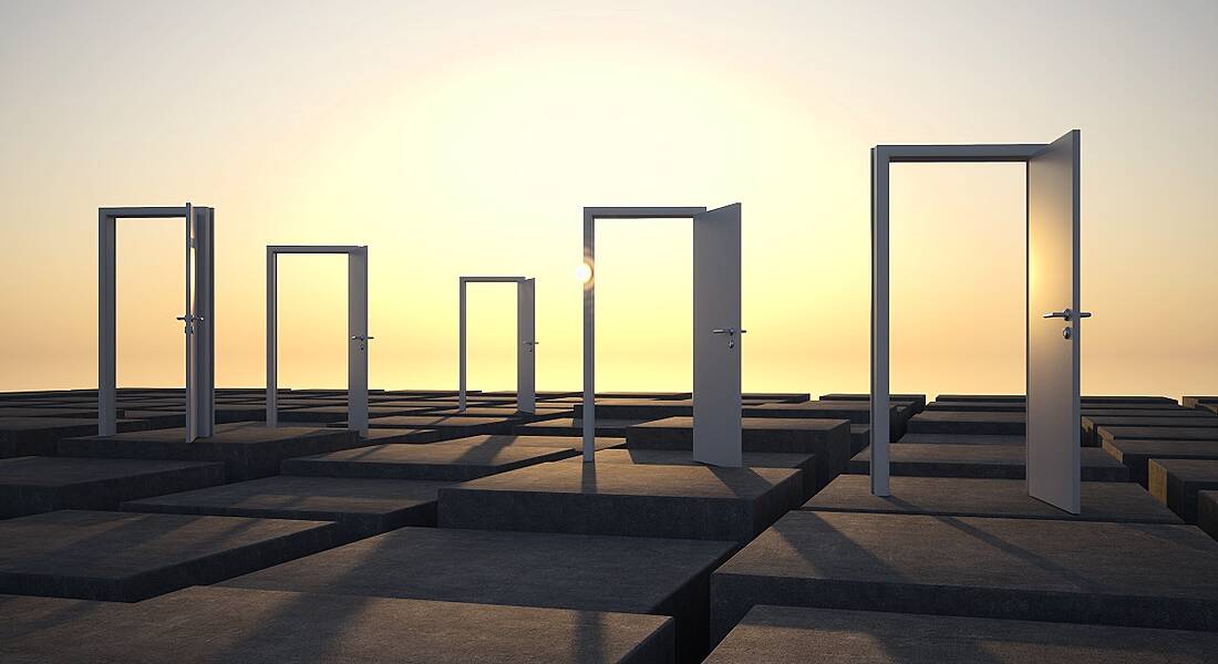 Abstract photo of open doors in an outdoor setting with sun rising behind them.