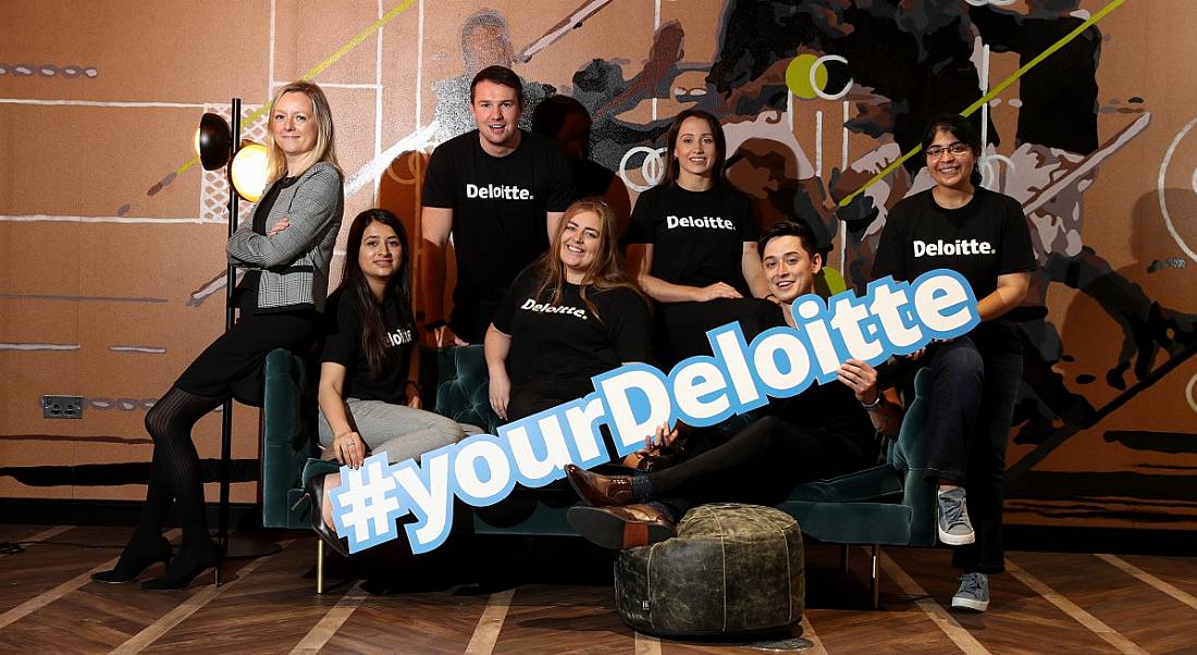 View of young people in Deloitte T-shirts holding 'Your Deloitte' sign.