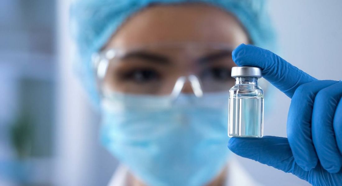 Close up photograph of a female scientist holding a vial, representing biotech.