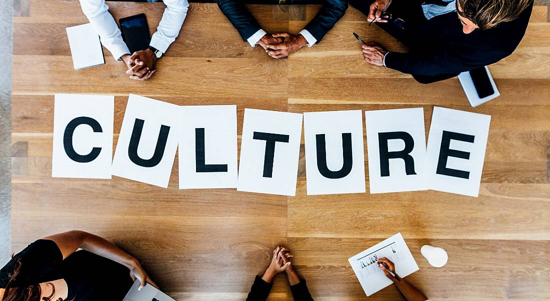 Group of business people with alphabet signs forming the word culture on the table. Top view of business people in a meeting.