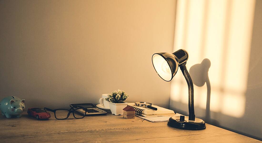 Working table with lamp, and evening light reflecting on wall in the background.