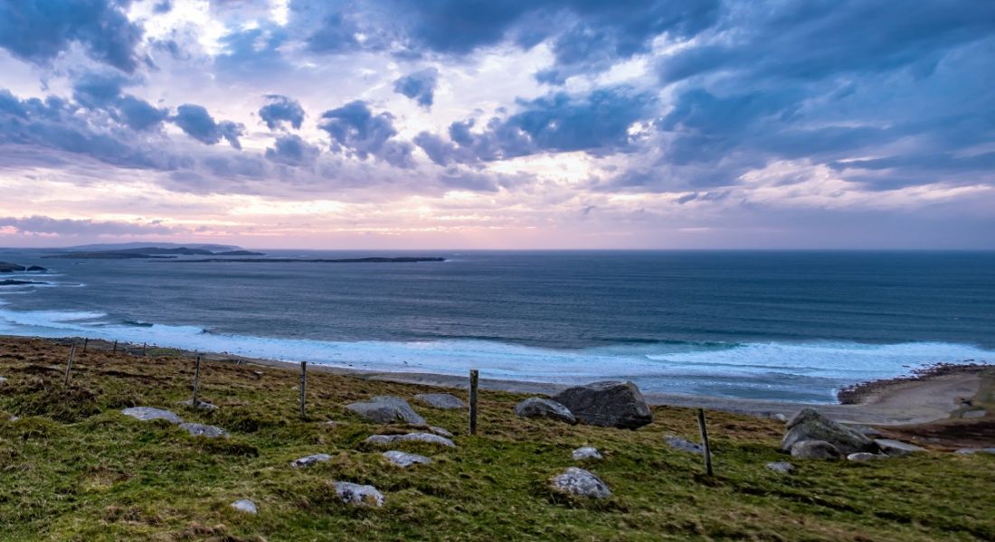 Photo of a Gaeltacht region in Ireland, with a rocky, grassy coastal area meeting the sea.