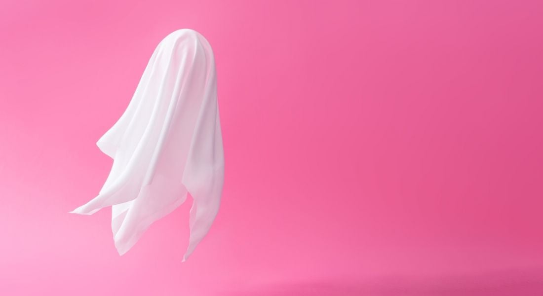 A floating sheet shaped like a ghost levitating against a lurid pink background.