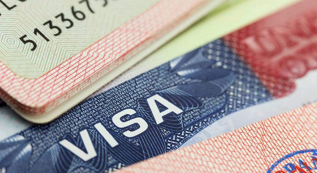 View of a staggered stack of multi-coloured and stamped visa papers for non-EEA citizens.