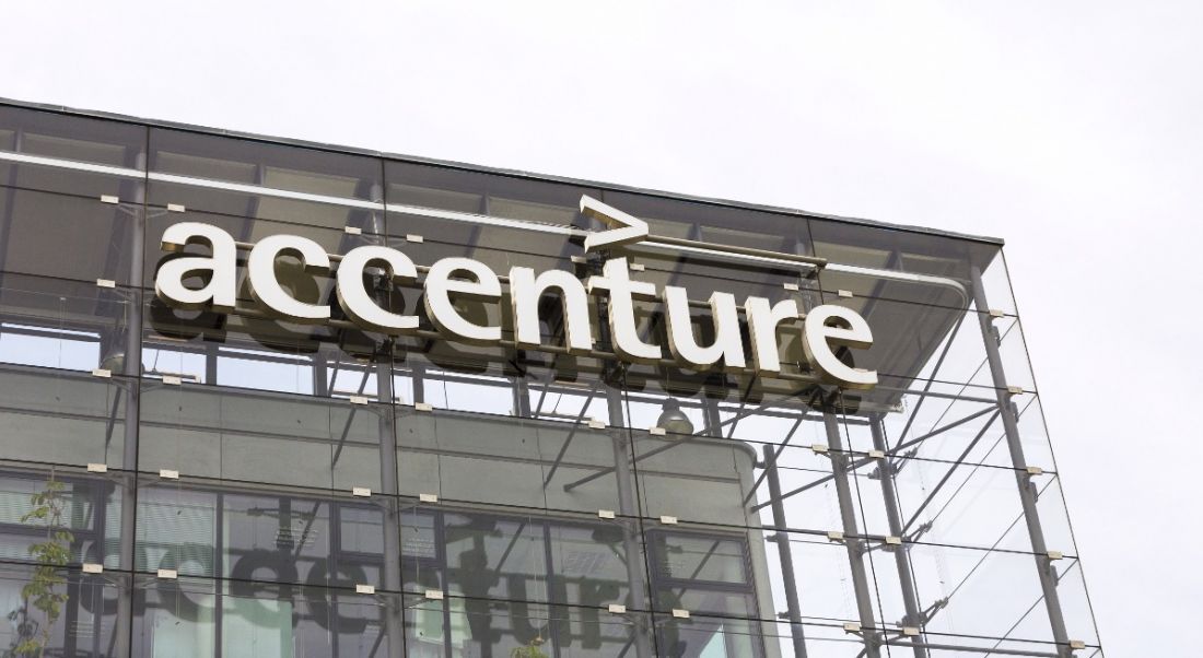 An Accenture logo on a glass building pictured on a grey and overcast day.