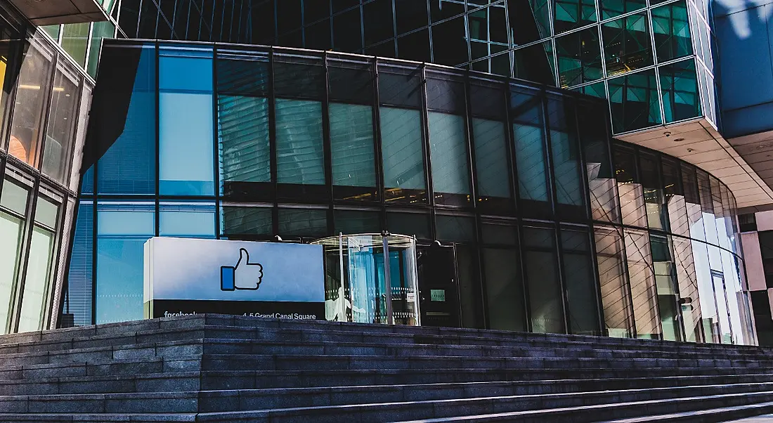 A view of the glass exterior and concrete steps leading up to the Facebook offices in Dublin on a clear day.