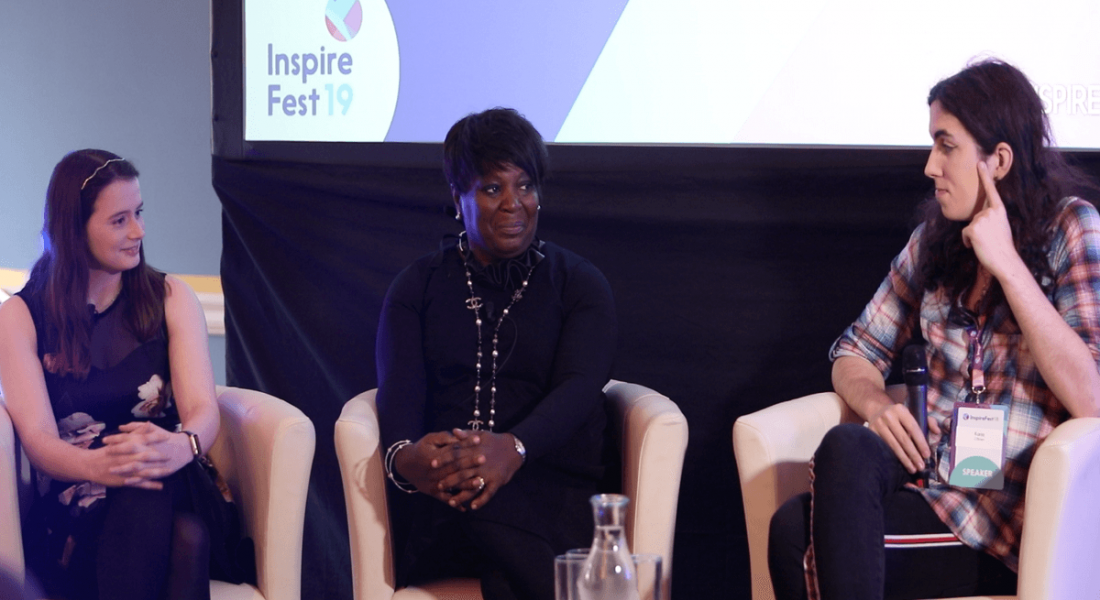 three women sitting on cream leather chairs discussing diversity against an Inspirefest backdrop.