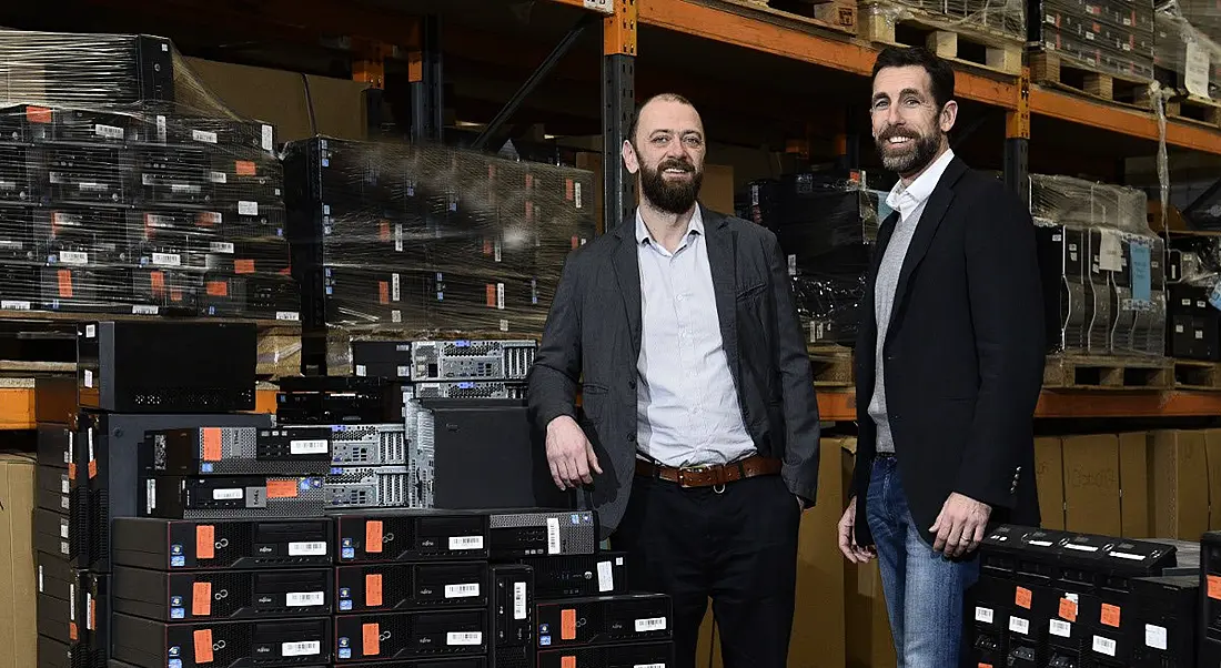 Two bearded men in sports jackets standing in a room full of IT equipment.